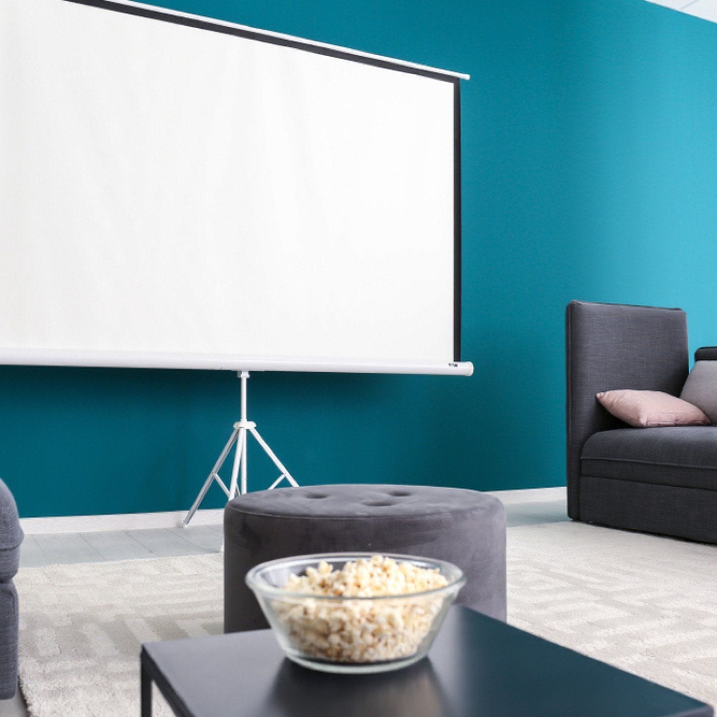 Basement home theatre with a projector screen, sofa and bowl of popcorn