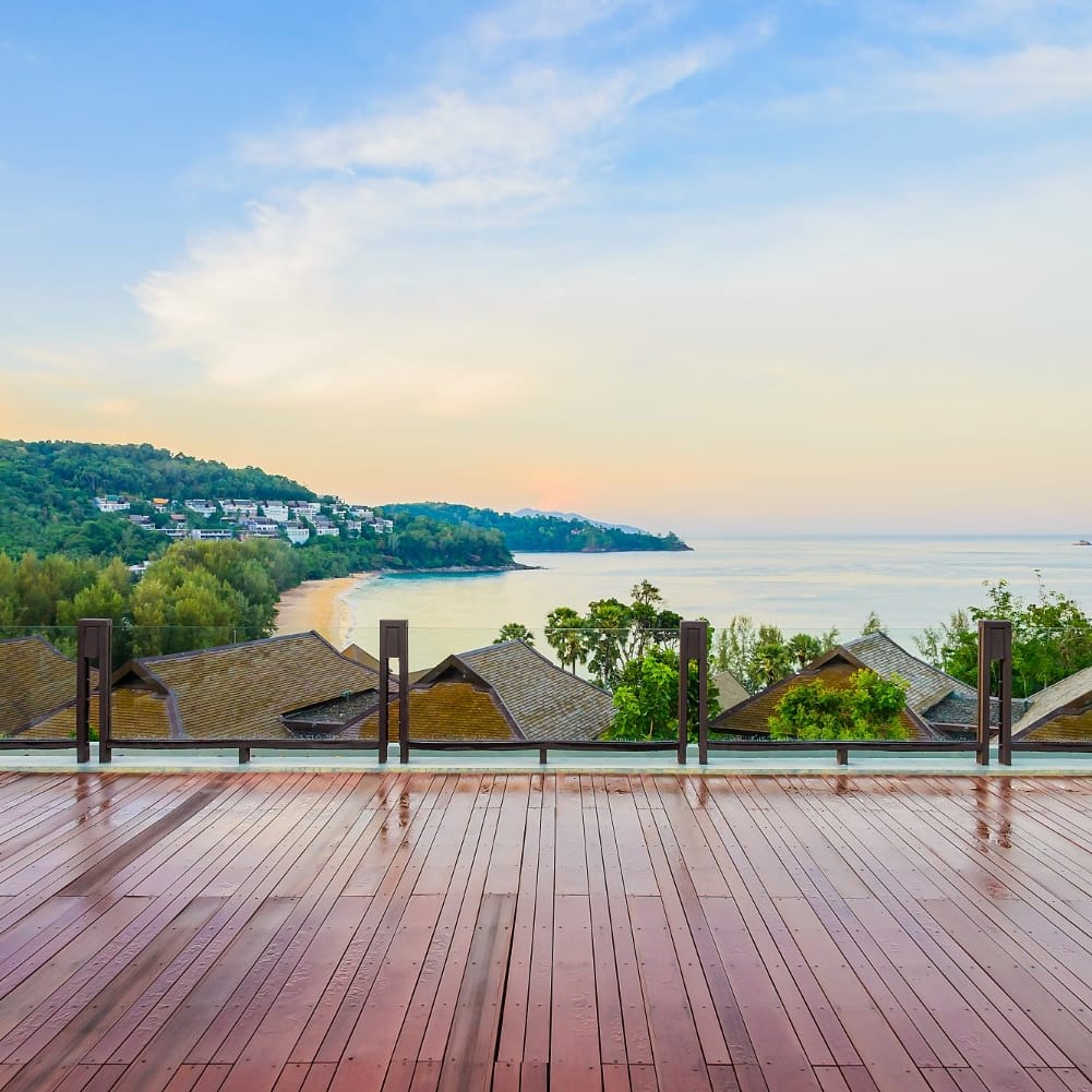 Hardwood deck and railing looking out over a bay at sunset