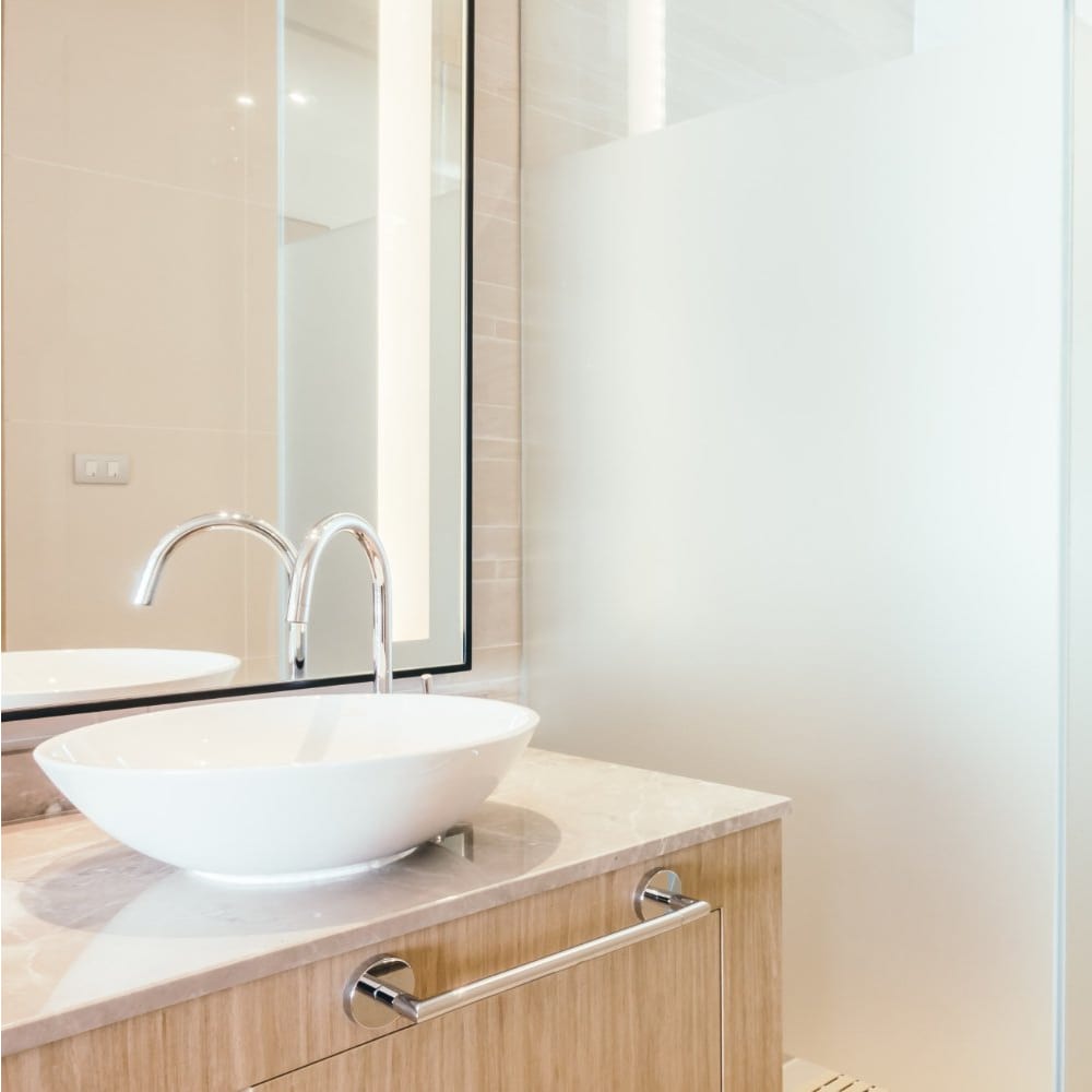Pale timber vanity with a white vessel basin and backlit mirror