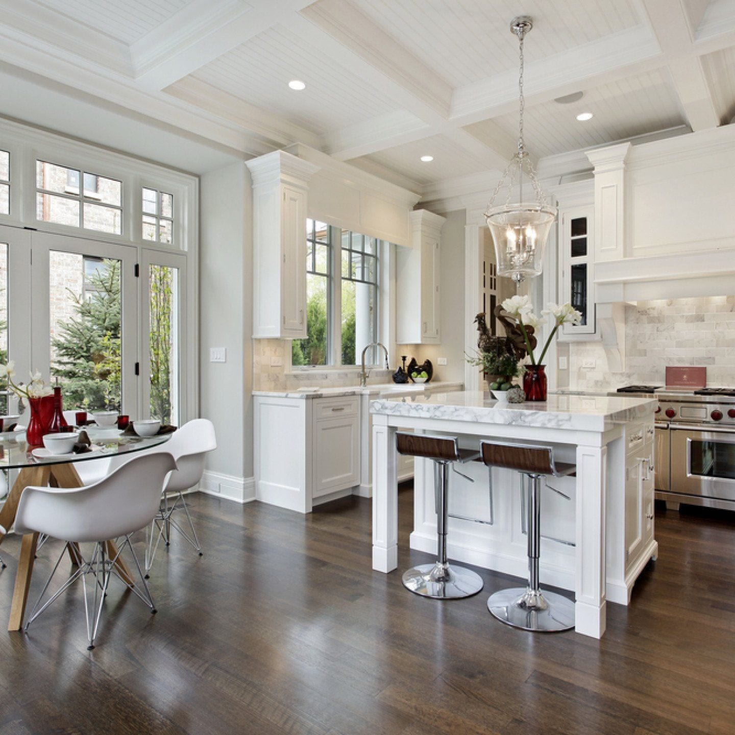 White kitchen with a coffered ceiling, marble island and dining area